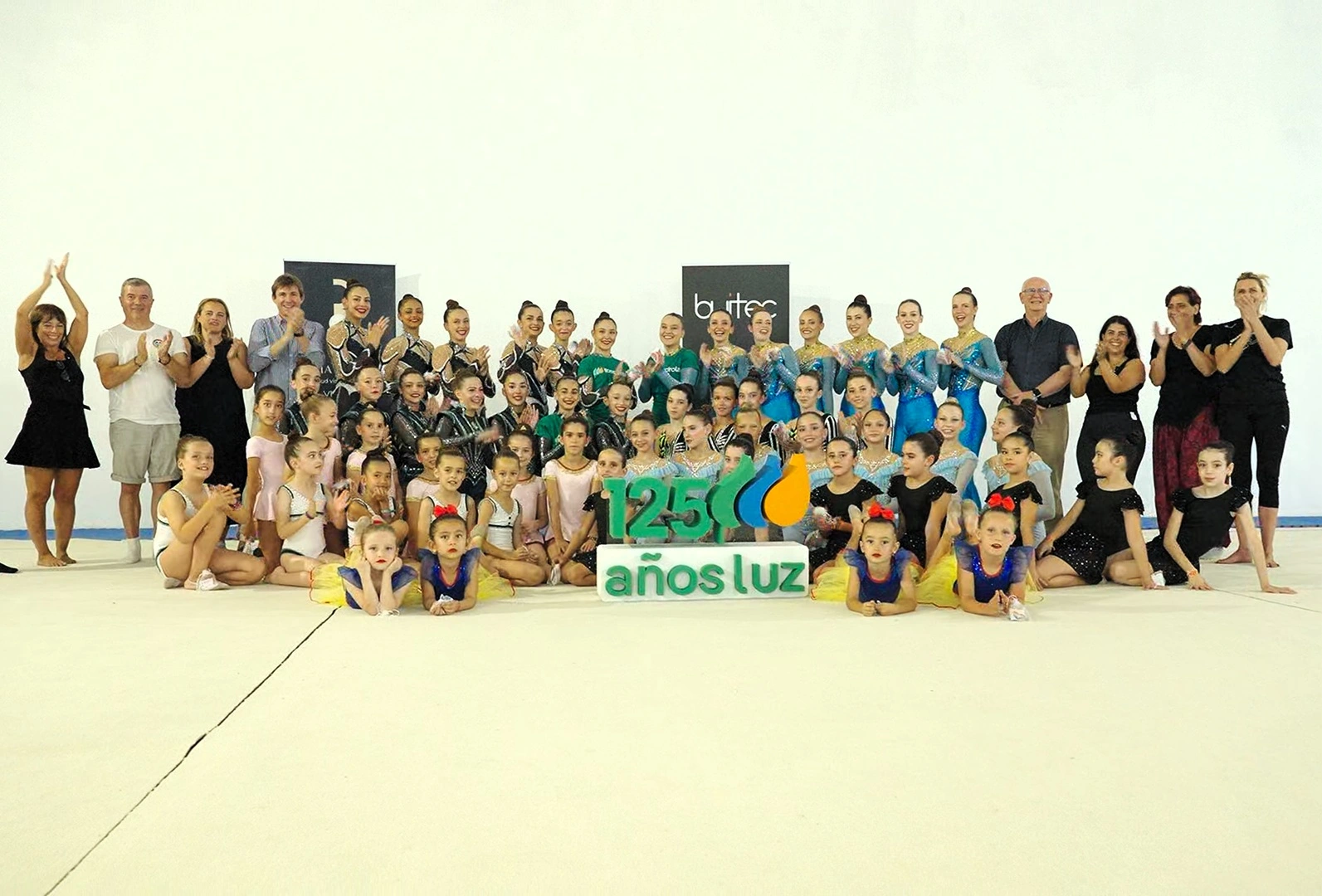 Grupo de niñas y adolescentes de un club de gimnasia rítmica posando junto a entrenadores y un panel con el logotipo de Iberdrola y el texto “125 años luz” durante la entrega del Premio Iberdrola Supera.