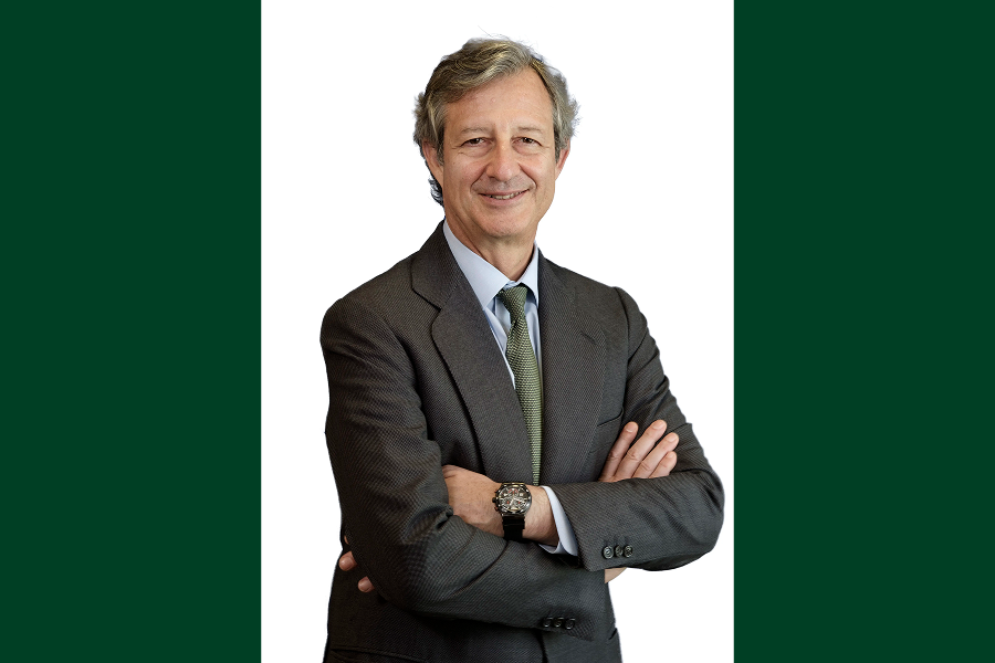 Retrato de directivo en traje con los brazos cruzados sobre fondo neutro blanco y verde.