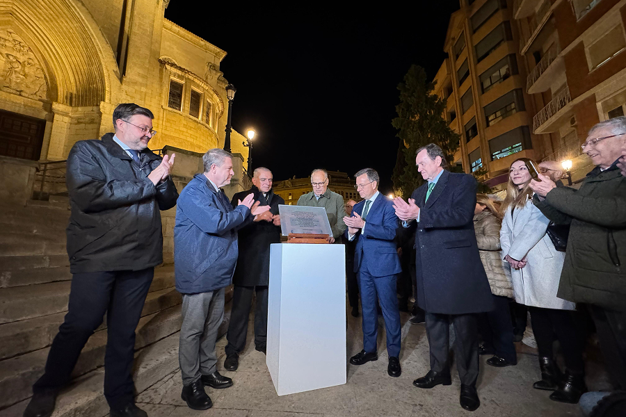 Autoridades presentan placa conmemorativa en acto nocturno junto a catedral iluminada.