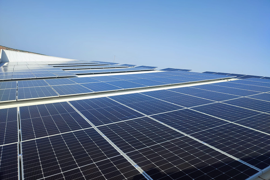 Paneles solares instalados en cubierta industrial, dispuestos en filas bajo cielo despejado