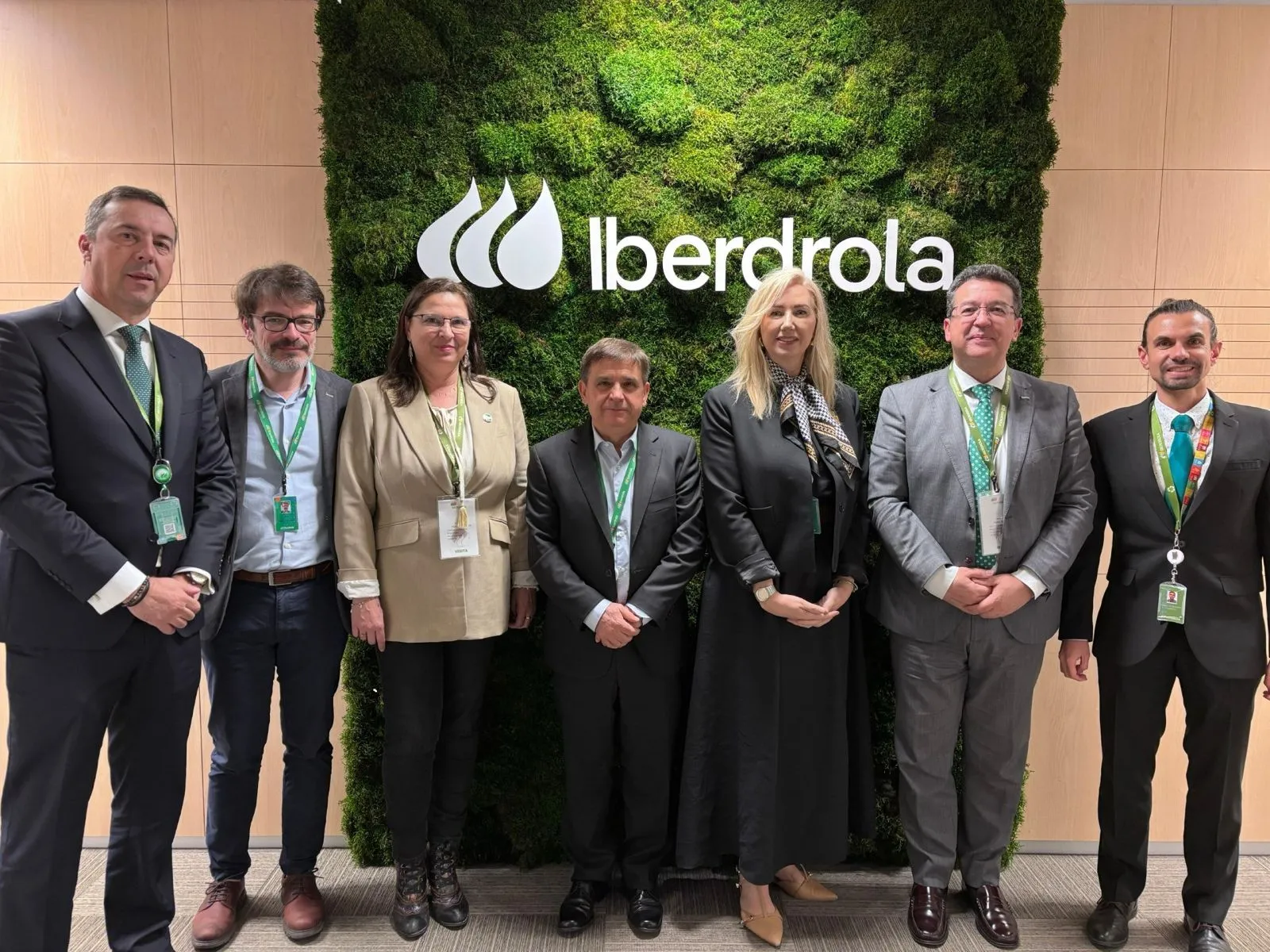 Management team poses in front of the Iberdrola logo on a green wall at the corporate headquarters