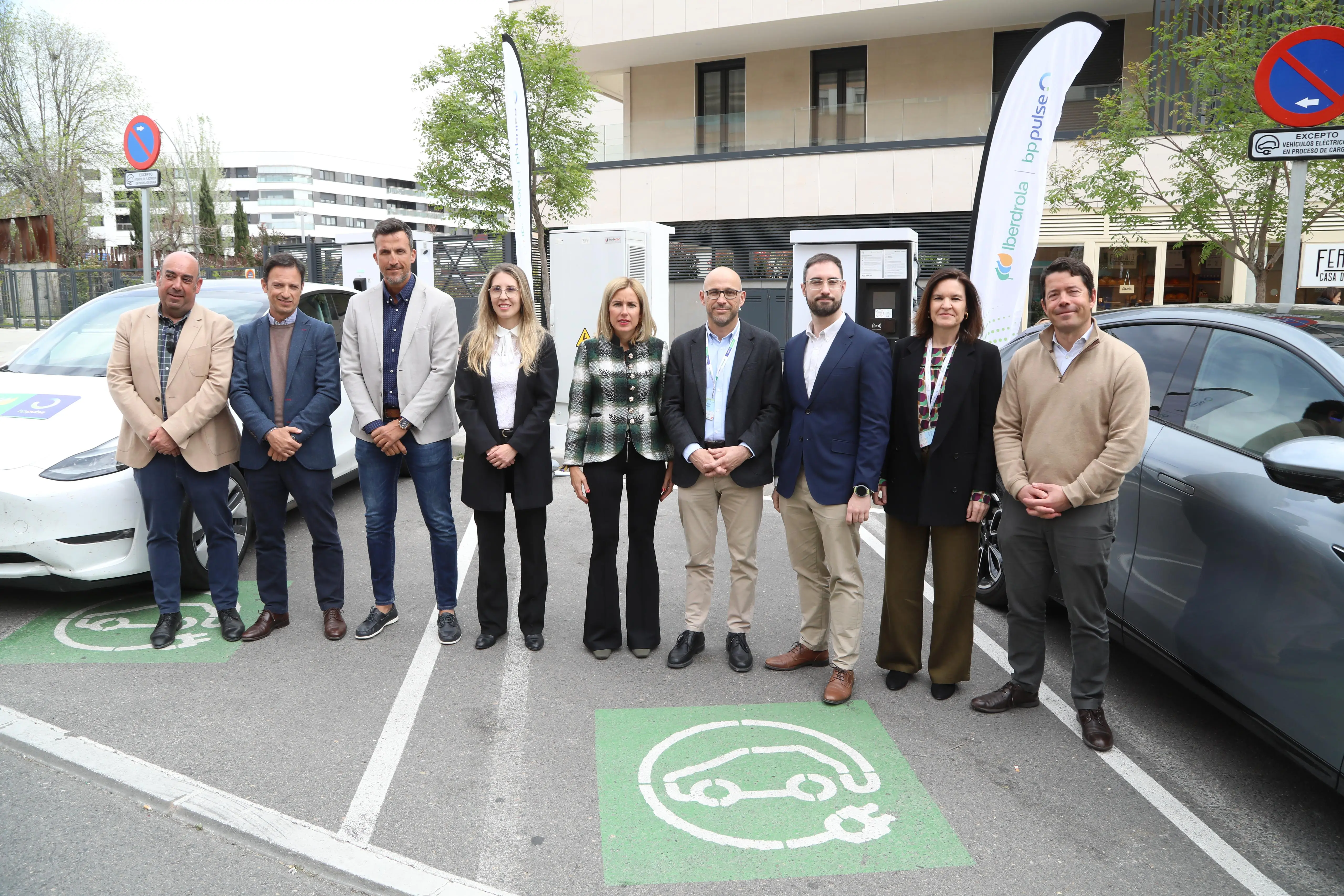 Group of people posing in front of an electric vehicle charging station in Alcobendas, with Iberdrola and bp pulse logos in the background.