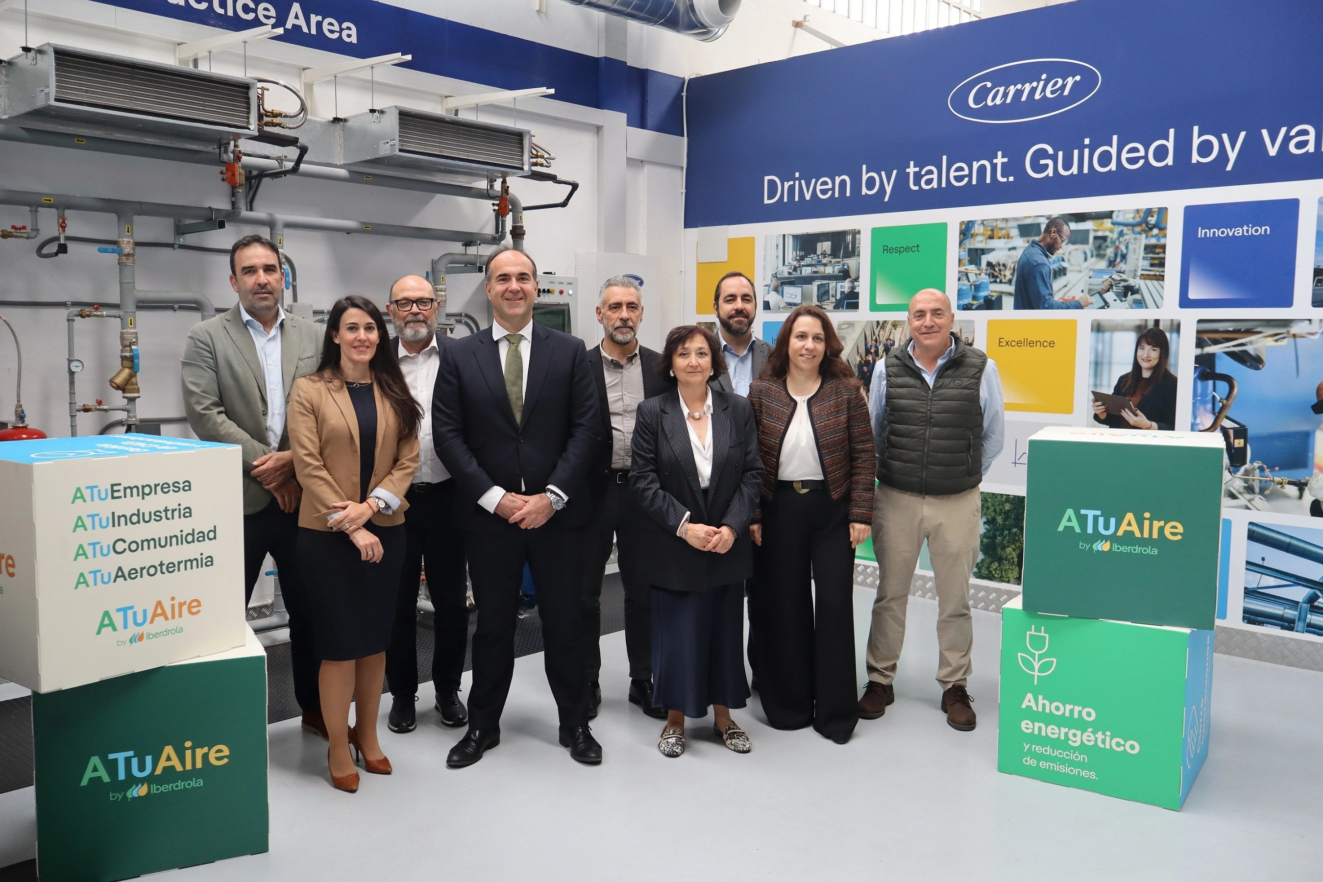 Grupo de profesionales posando en instalación industrial junto a equipos de climatización y señalización de soluciones energéticas.
