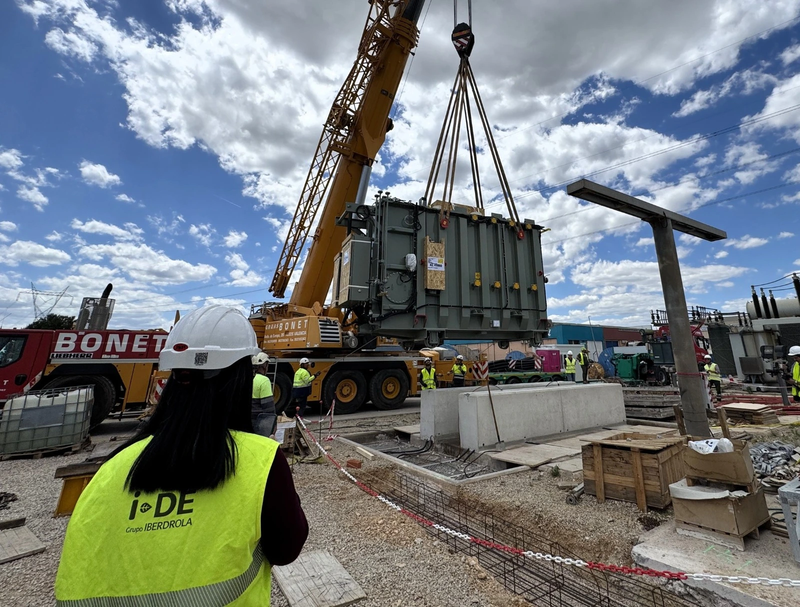 Instalación de un transformador eléctrico en una subestación, con personal técnico de i-DE Iberdrola y una grúa industrial.