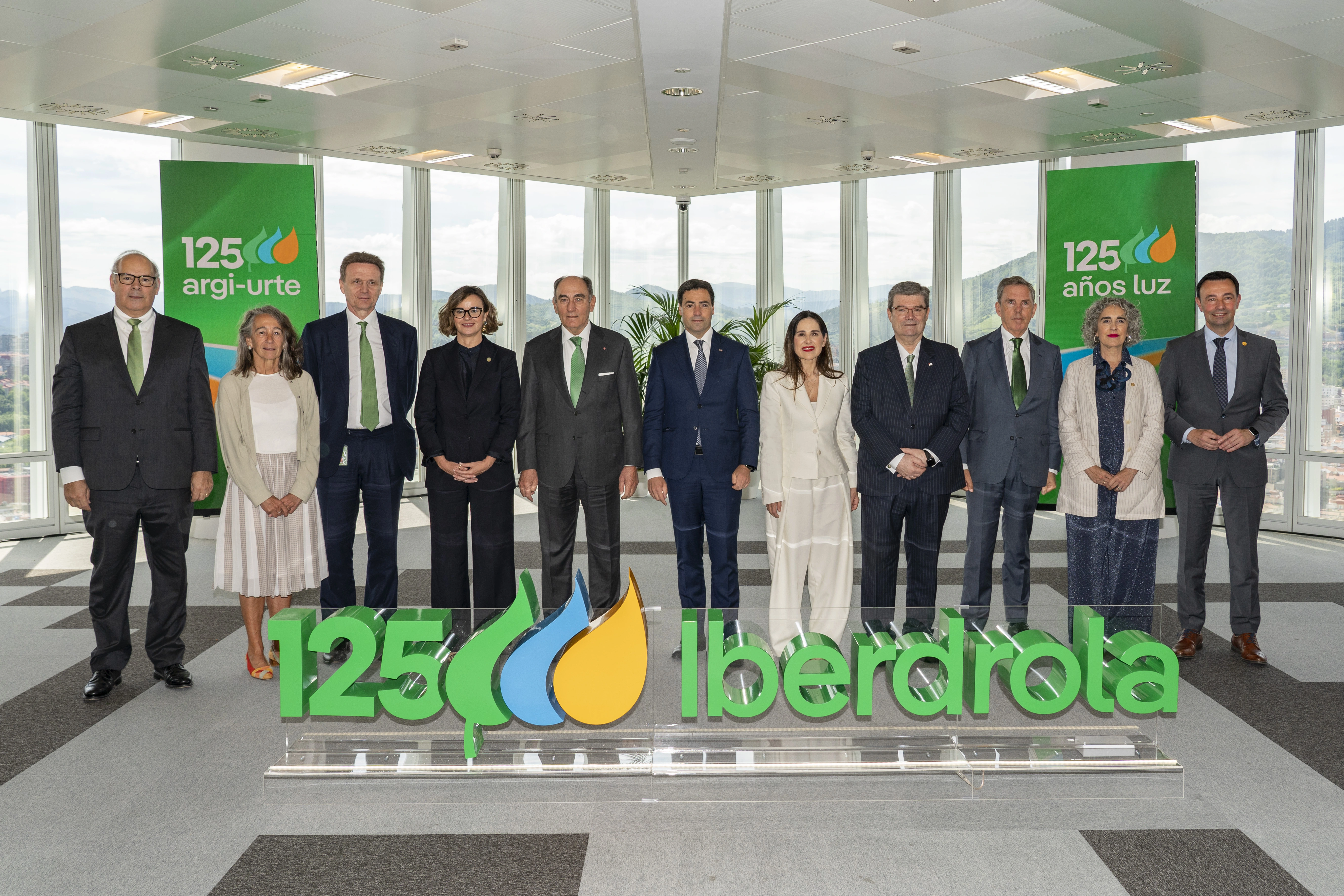 Grupo de directivos y ejecutivos posando frente a un cartel que celebra los 125 años de Iberdrola en Bilbao.