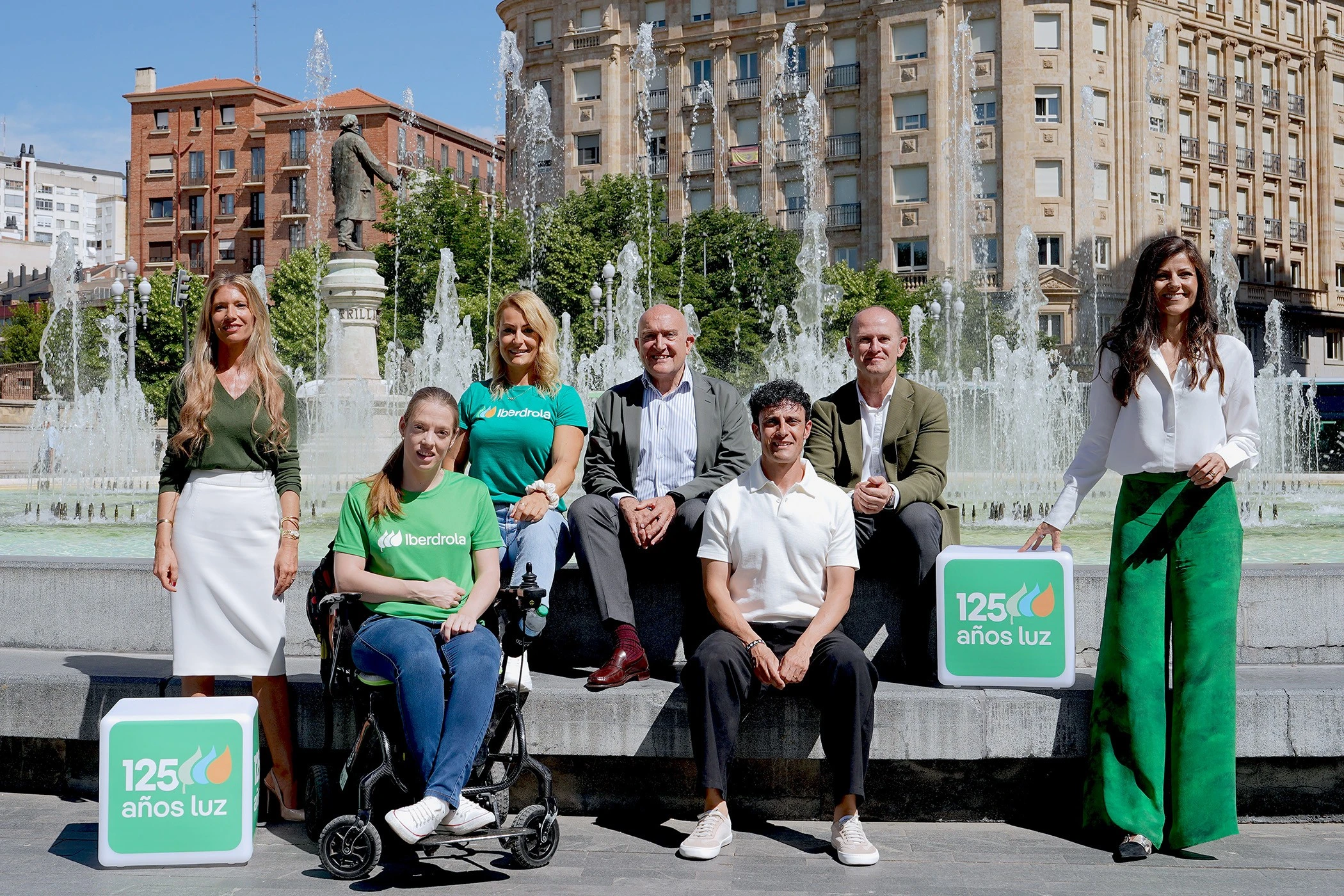 Grupo de siete personas posando frente a una fuente urbana con edificios de fondo, celebrando los 125 años de Iberdrola.