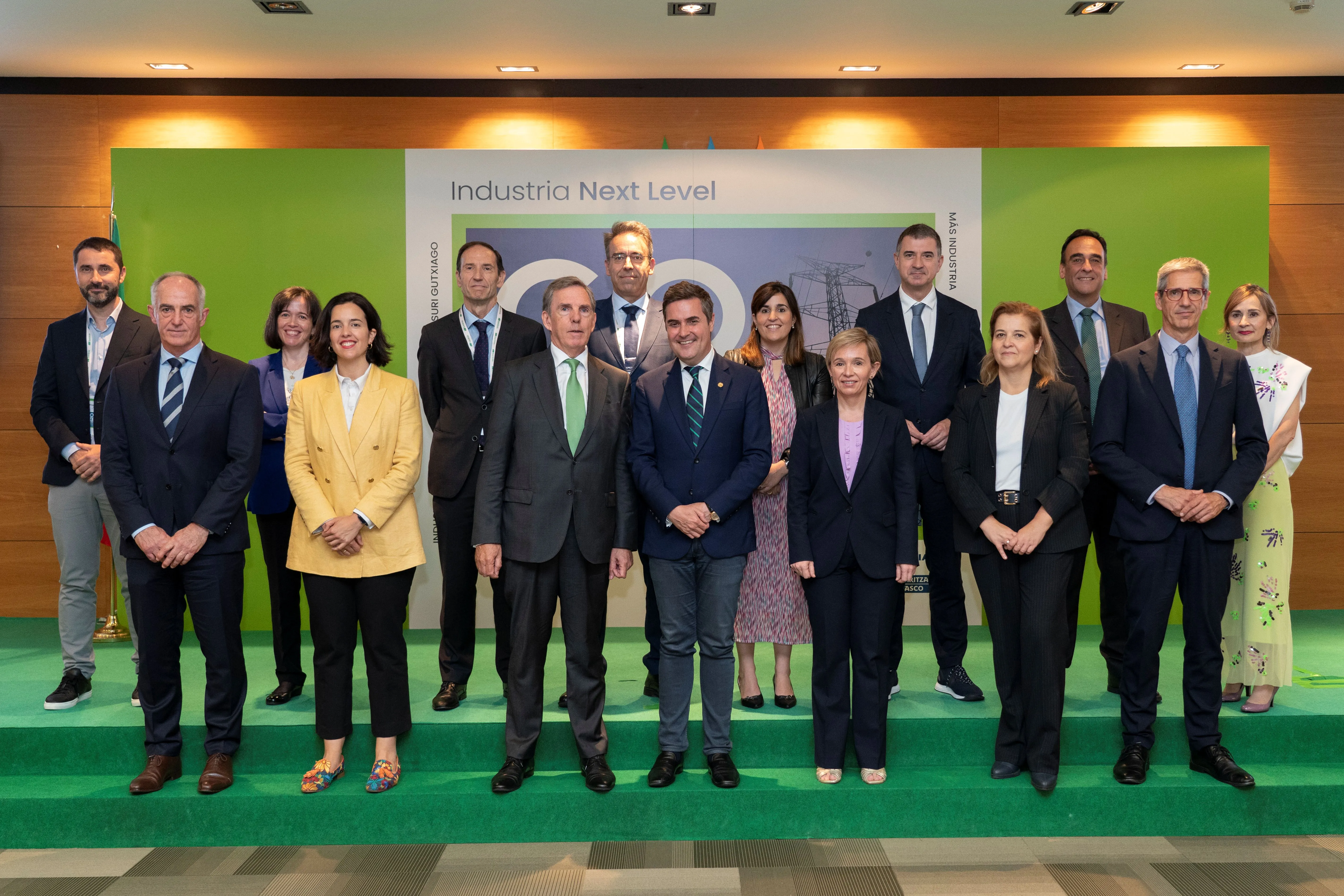 Grupo de quince personas posando frente a un panel con el texto “Industria Next Level” durante un evento corporativo, vestidas de forma formal.
