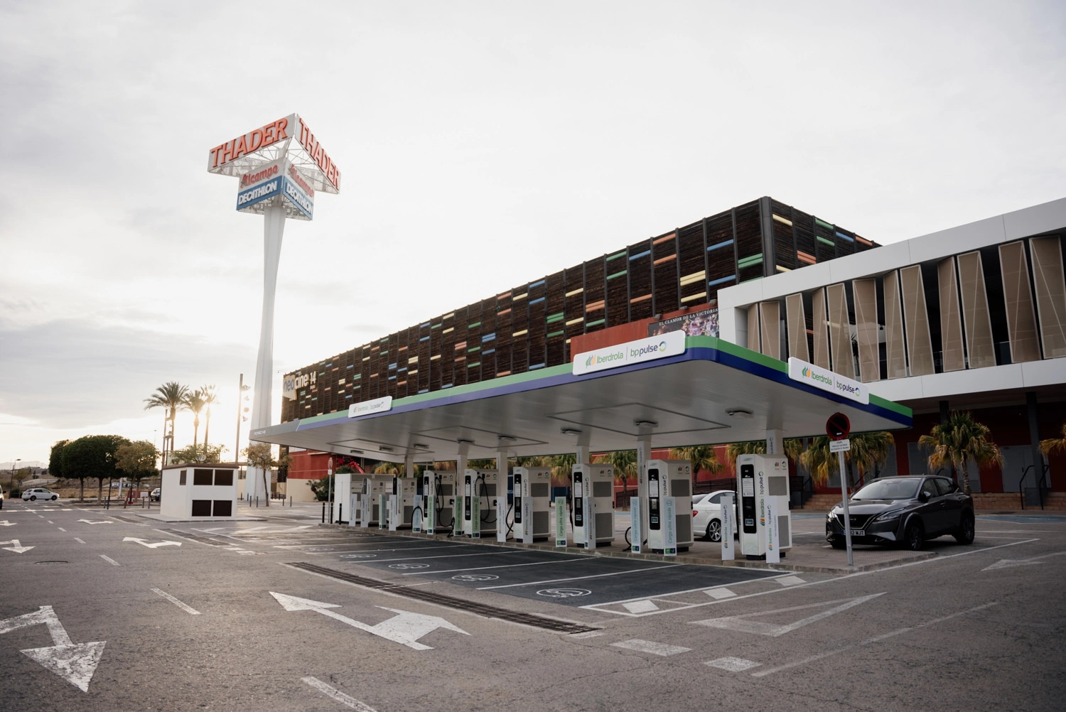 Estación de recarga para vehículos eléctricos junto a un edificio comercial.