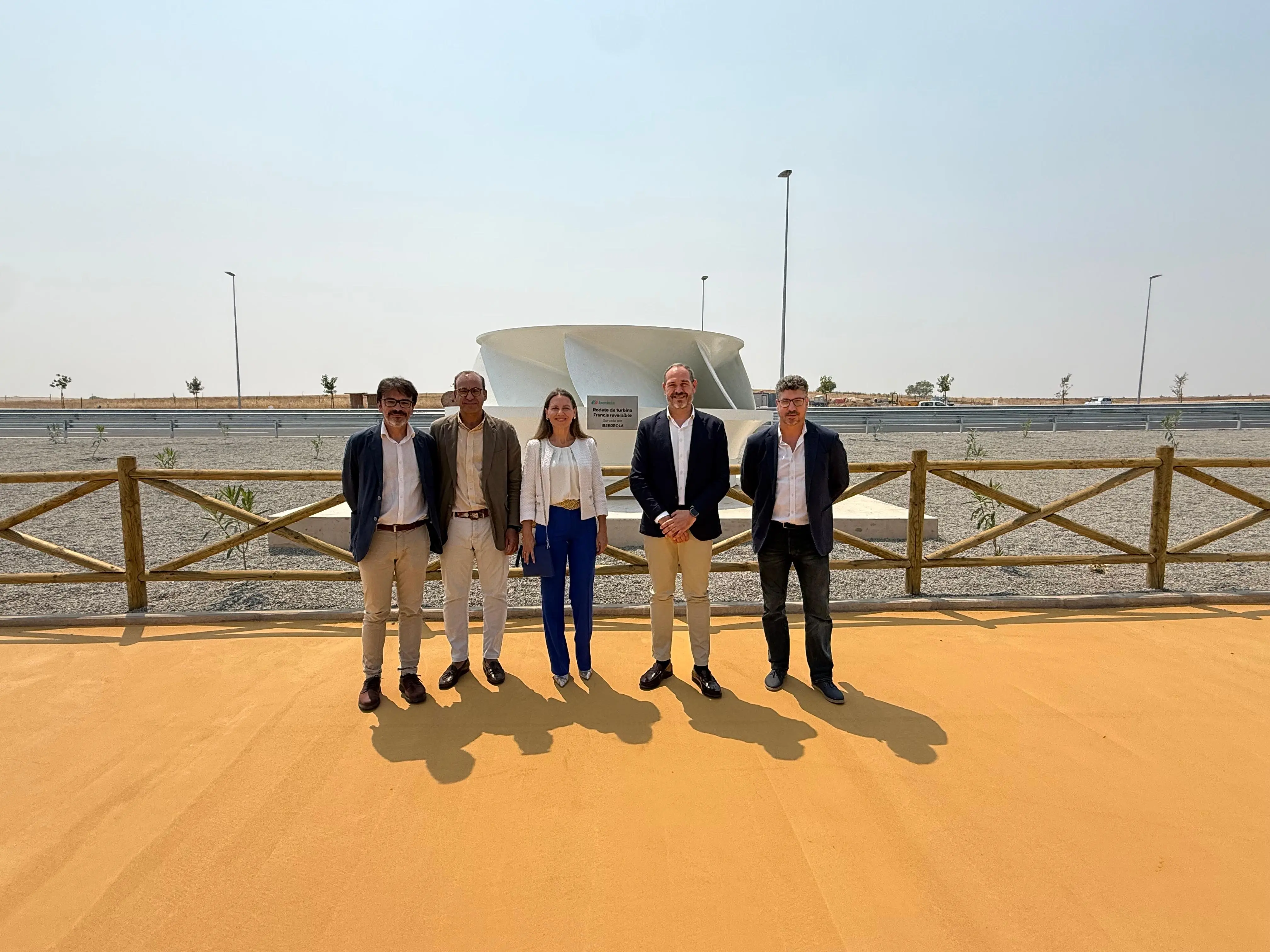 Five people posing next to a renewable energy installation in an outdoor industrial area.