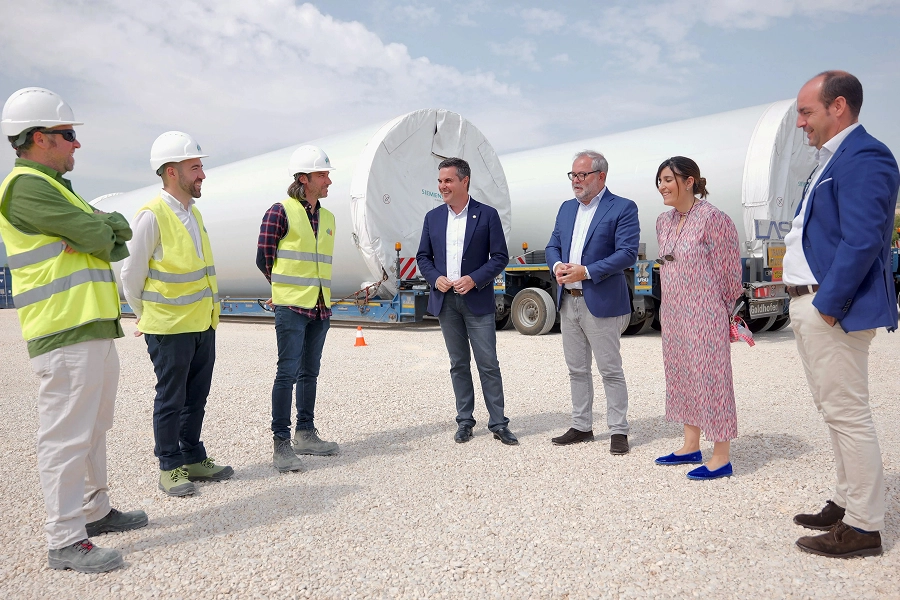 Grupo de profesionales durante una visita a una instalación eólica con componentes de aerogeneradores.
