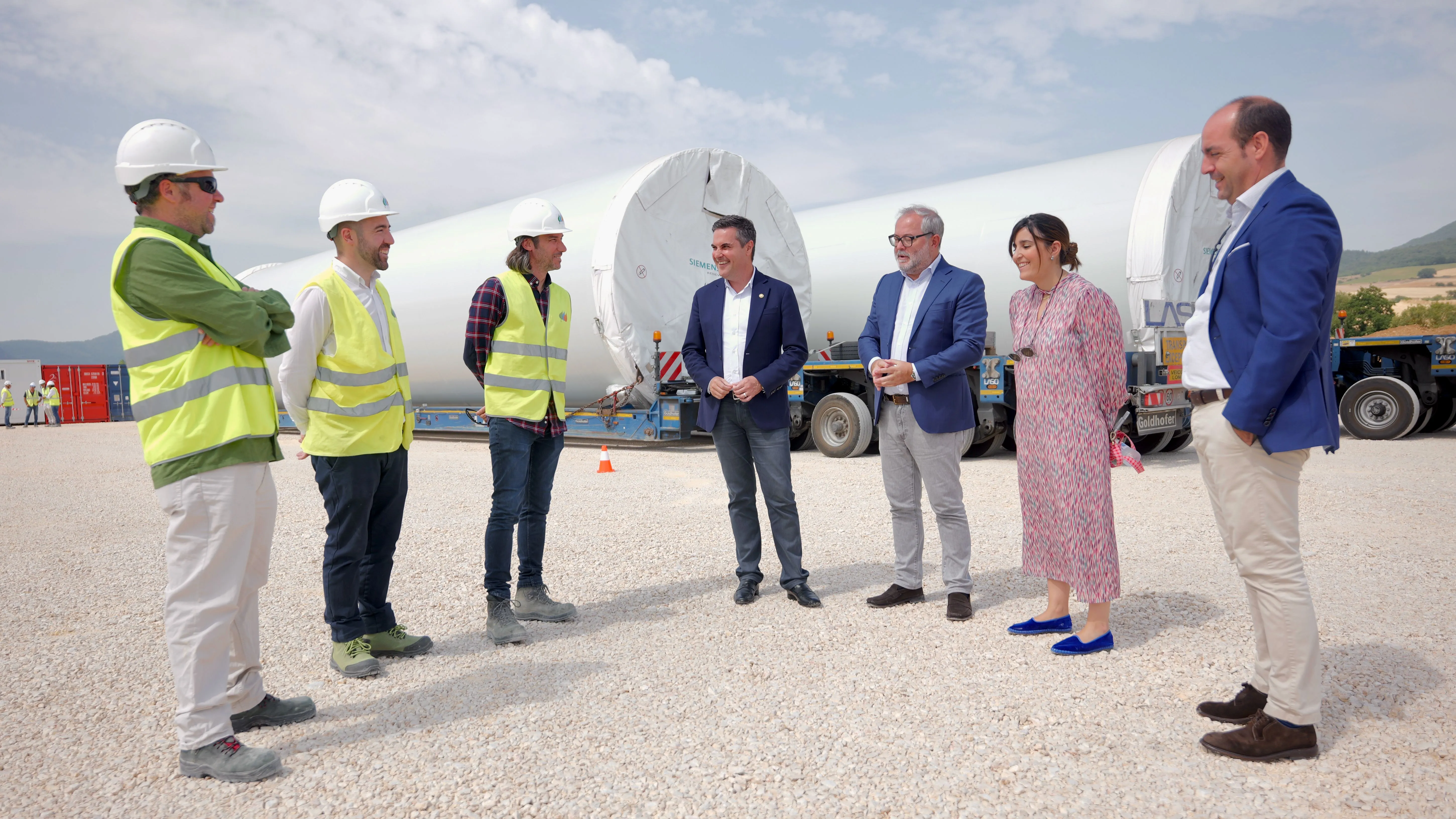 Grupo de profesionales durante una visita a una instalación eólica con componentes de aerogeneradores.