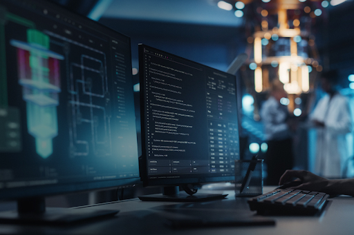 Pantallas de computadora mostrando gráficos y código, con una persona trabajando en el teclado. Al fondo, se pueden ver personas en un entorno de laboratorio de alta tecnología.